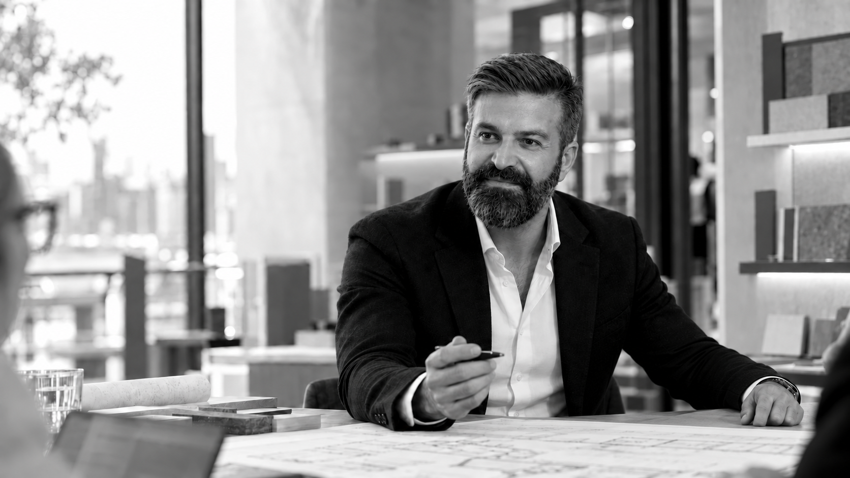 Hakan Aydin, Gründer und Projektleiter von Hanse Lotse, mit Stift am Planungstisch vor Materialmustern.